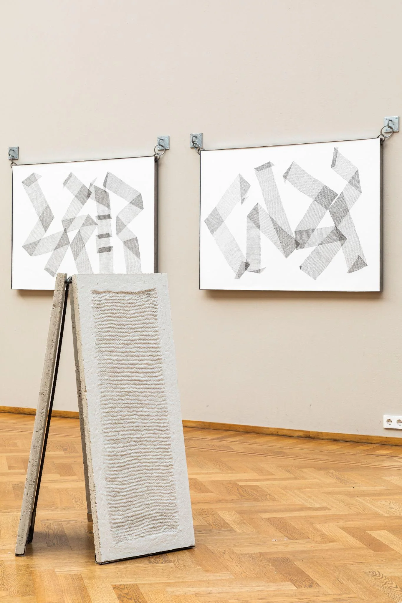 Sculptural panel on a support with framed drawings behind it