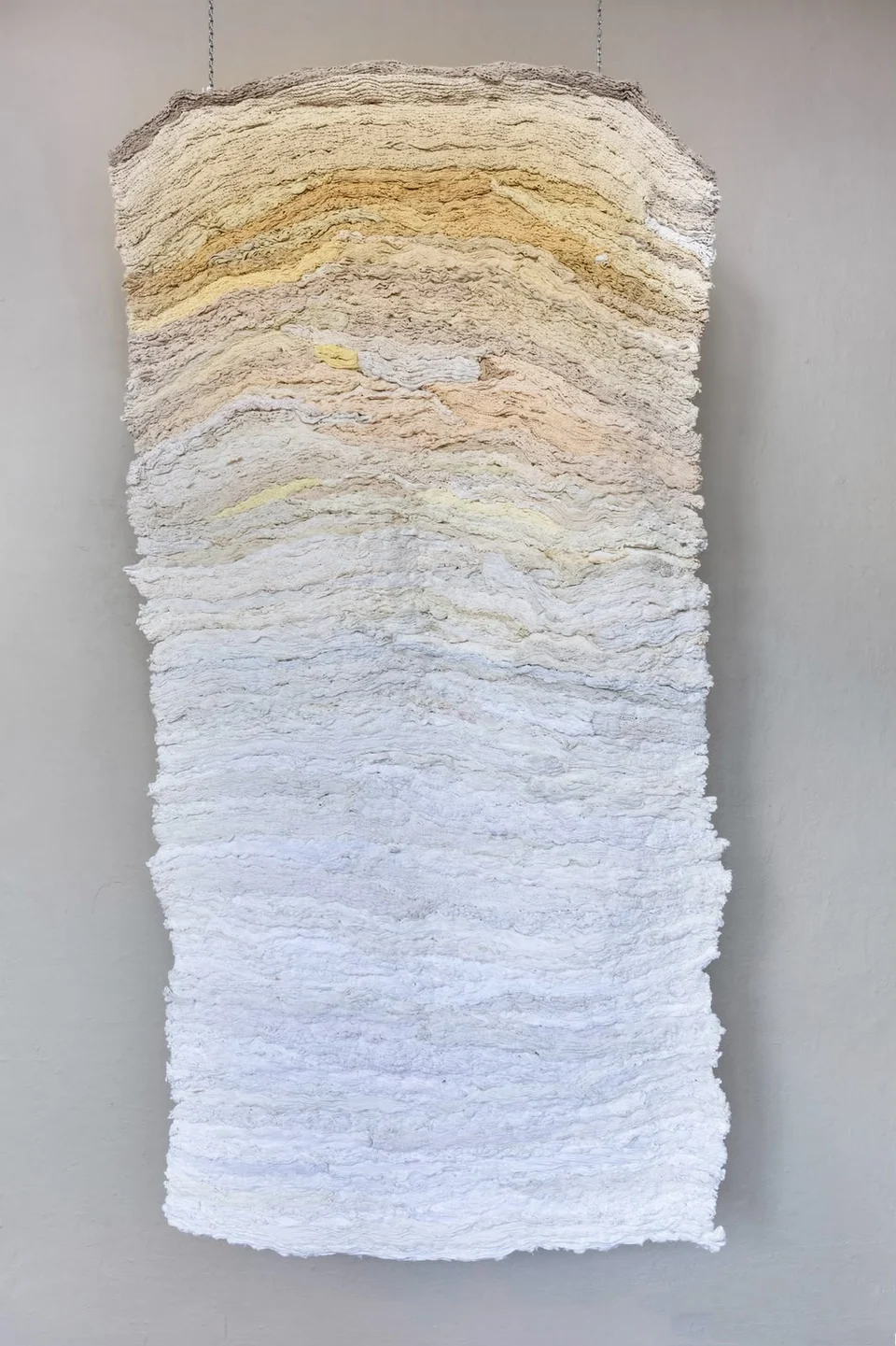 Suspended textile with layered cream, sand and white fibres